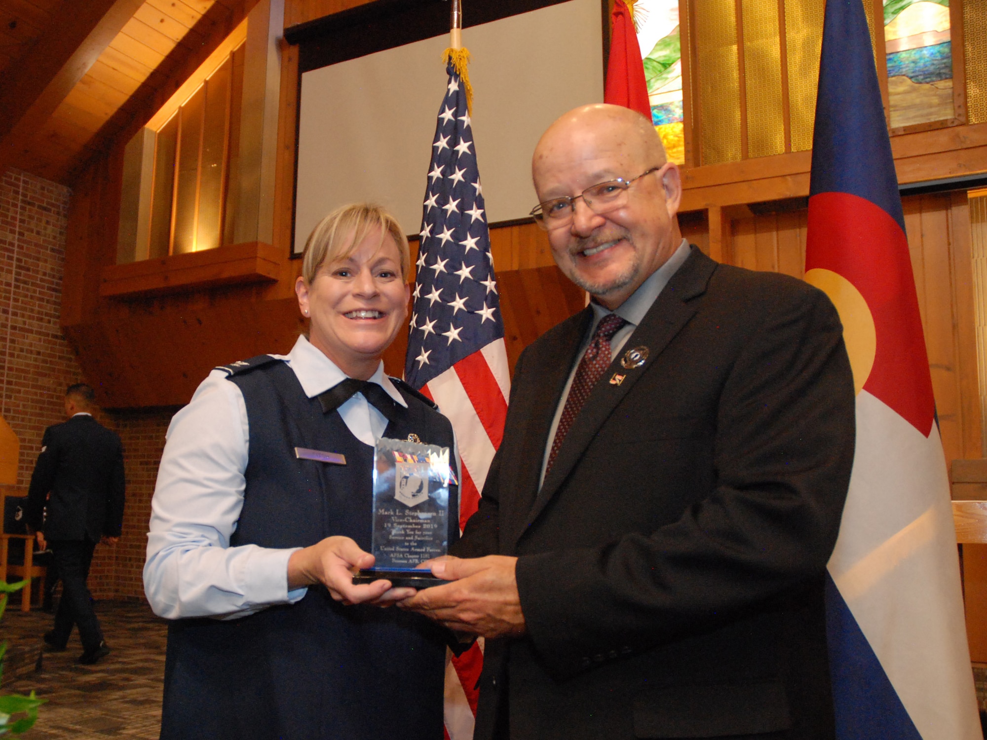 Mark L. Stephensen II, vice-chairman for the National League of POW/MIA families, right, accepts an award from Col. Jennifer Fitch, individual mobilization augmentee to the 21st Space Wing commander, Sept. 19, 2019 at Peterson Air Force Base, Colorado. Fitch presented the award as part of POW/MIA Remembrance Week to thank Stephensen for his service and sacrifice in working toward full accounting of all unreturned veterans. (U.S. Air Force photo by Griffin Swartzell)