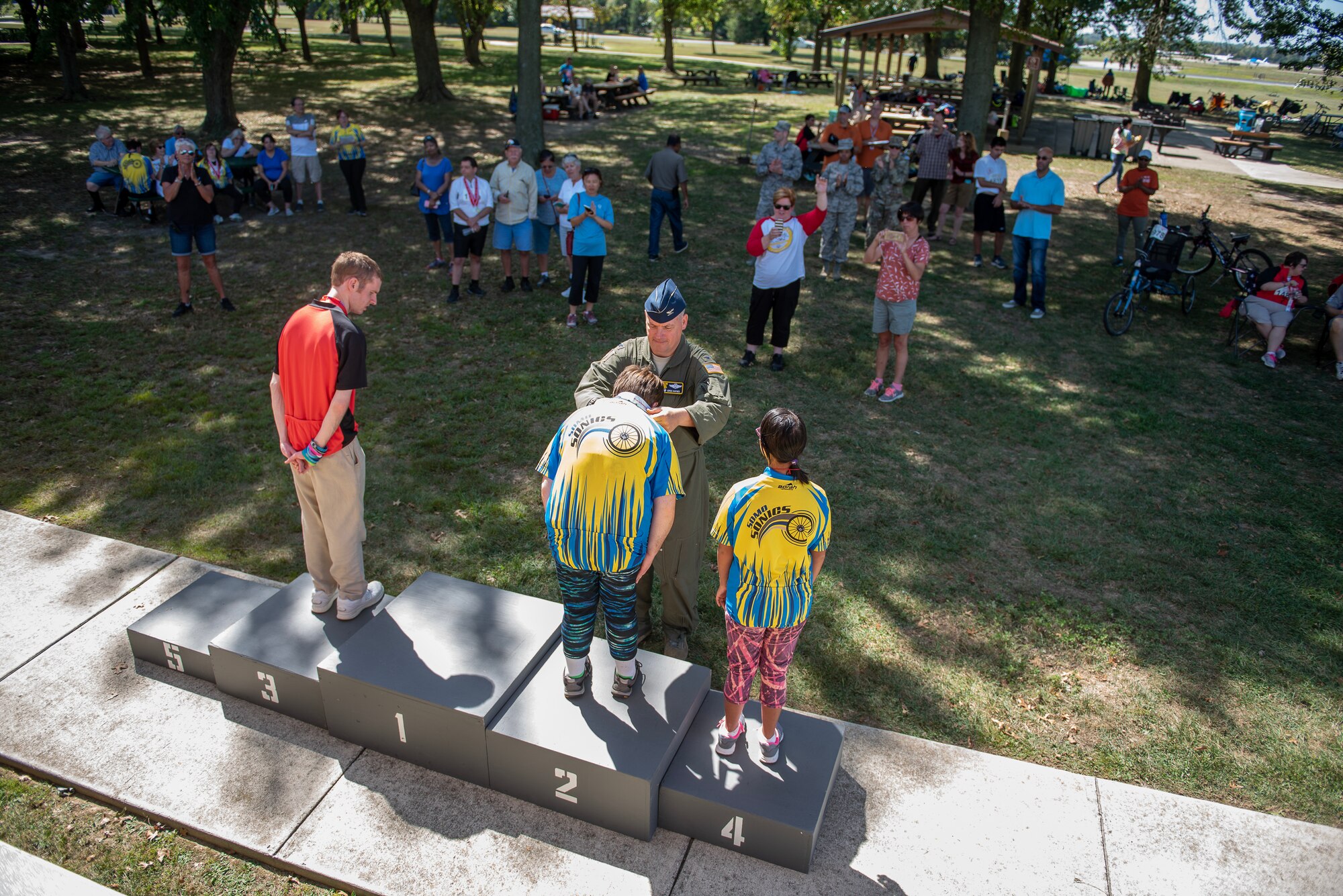 Col. Gregory P. Haynes, 512th Airlift Wing commander, presents winning athletes with medals during the 2019 Special Olympics Cycling Event at Dover Air Force Base, Delaware, Sept. 21, 2019. The Special Olympics Delaware organization offers a year-round sports training and competition program with over 4,000 volunteers. (U.S. Air Force photo by Staff Sgt. Damien Taylor)