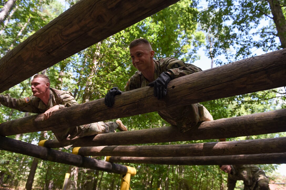 U.S. Army Pvt. Jeffrey Lawless (left) and Pfc. James Whitaker (right), Charlie Company, 222nd Battalion, 1st Aviation Regiment, 128th Aviation Brigade UH-60 Black Hawk helicopter advanced individual training students, climb over logs during a field training exercise at Joint Base Langley-Eustis, Virginia, Sept. 18, 2019.