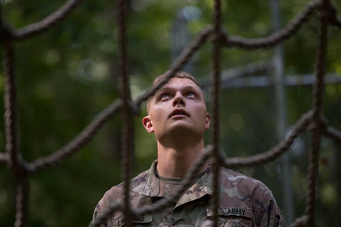 U.S. Army Pvt. Jeffrey Lawless, Charlie Company, 222nd Battalion, 1st Aviation Regiment, 128th Aviation Brigade UH-60 Black Hawk helicopter advanced individual training student, looks up at a cargo net during a field training exercise at Joint Base Langley-Eustis, Virginia, Sept. 18, 2019.