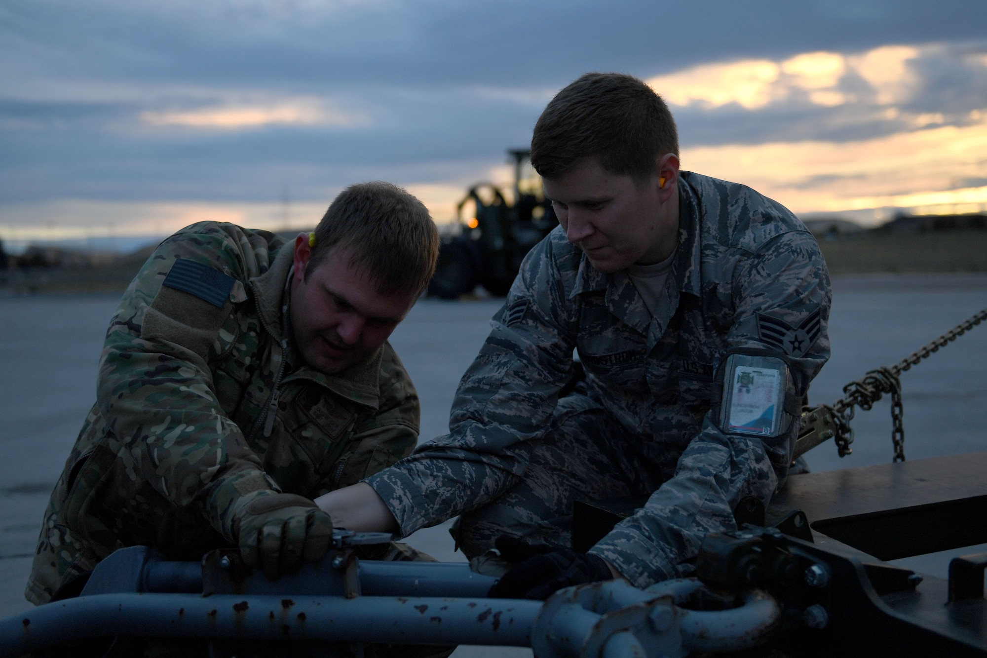 Two men work on a piece of equipment.