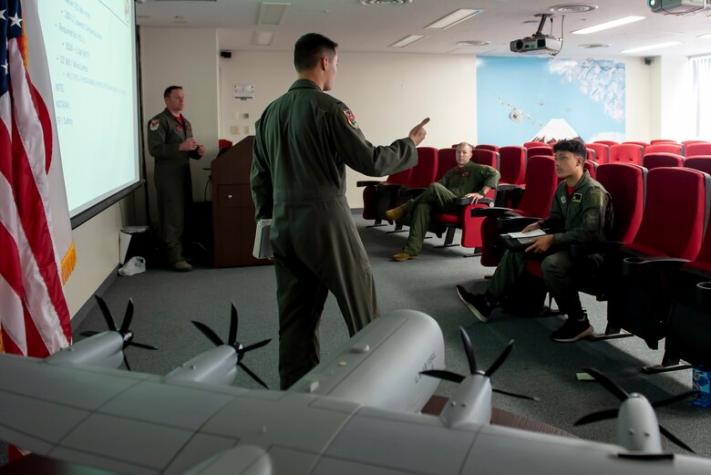 Joey DeGrella, Yokota High School senior and Junior Reserve Officer Training Corps. class commander, is given a mission brief by 1st Lt. Christopher Gullo, 36th Airlift Squadron C-130J Super Hercules pilot, during the Pilot for a Day program, Sept. 20, 2019, at Yokota Air Base, Japan