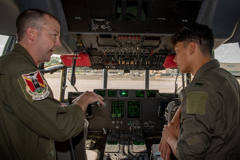 Master Sgt. Michael McArty, 36th Airlift Squadron C-130J Super Hercules instructor loadmaster, explains the controls of a C-130J Super Hercules cockpit to Joey DeGrella, Yokota High School senior and Junior Reserve Officer Training Corps. class commander, who was selected as the Pilot for a Day program, Sept. 20, 2019, at Yokota Air Base, Japan.