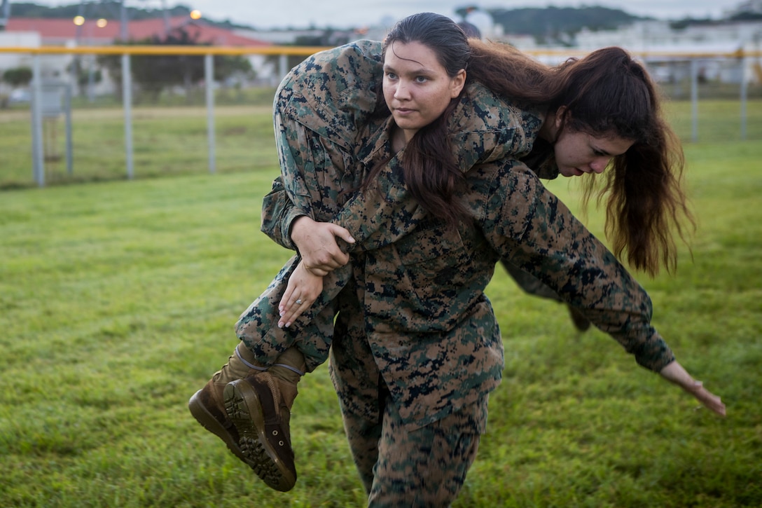 A female Marine carries another female Marine.
