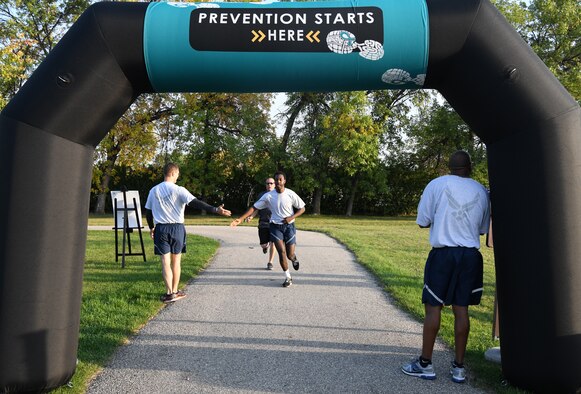 Airmen and family members from the 319th Reconnaissance Wing begin a Suicide Awareness 5K Sept. 20, 2019, on Grand Forks Air Force Base, North Dakota. Squadrons and flights were encouraged to attend the 5K in groups wearing their morale shirts and carrying unit guidons. (U.S. Air Force photo by Airman 1st Class Brody Katka)