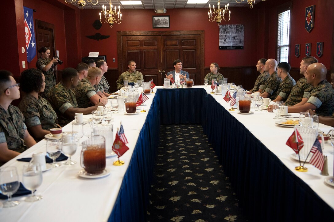 Defense Secretary Dr. Mark T. Esper sits at a large table with a group of people.