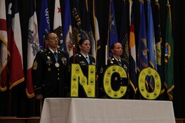 1st Sgt. Paul D. Gomez, first sergeant, Headquarters and Headquarters Company, Special Troops Battalion, 1st Theater Sustainment Command (TSC), stands with Master Sgt. Catherine Adams, senior mortuary affairs noncommissioned officer (NCO), Support Operations (SPO), 1st TSC, right, and Sgt. 1st Class Kerrilee Case, maintenance management NCO, SPO, 1st TSC, far right, during a 1st TSC NCO induction ceremony Aug. 27, 2018.