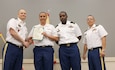 1st Sgt. Paul D. Gomez, first sergeant, Headquarters and Headquarters Company (HHC), Special Troops Battalion (STB), 1st Theater Sustainment Command (TSC), far right, stands with (left to right), Lt. Col. James Crocker, commander, STB, 1st TSC, Pfc. Michael Washington Jr., HHC, STB, 1st TSC, and Staff Sgt. Levi Gadson, supply sergeant, HHC, STB, 1st TSC, during an awards presentation at Haszard Auditorium on Fort Knox, Ky., Aug. 2, 2019.