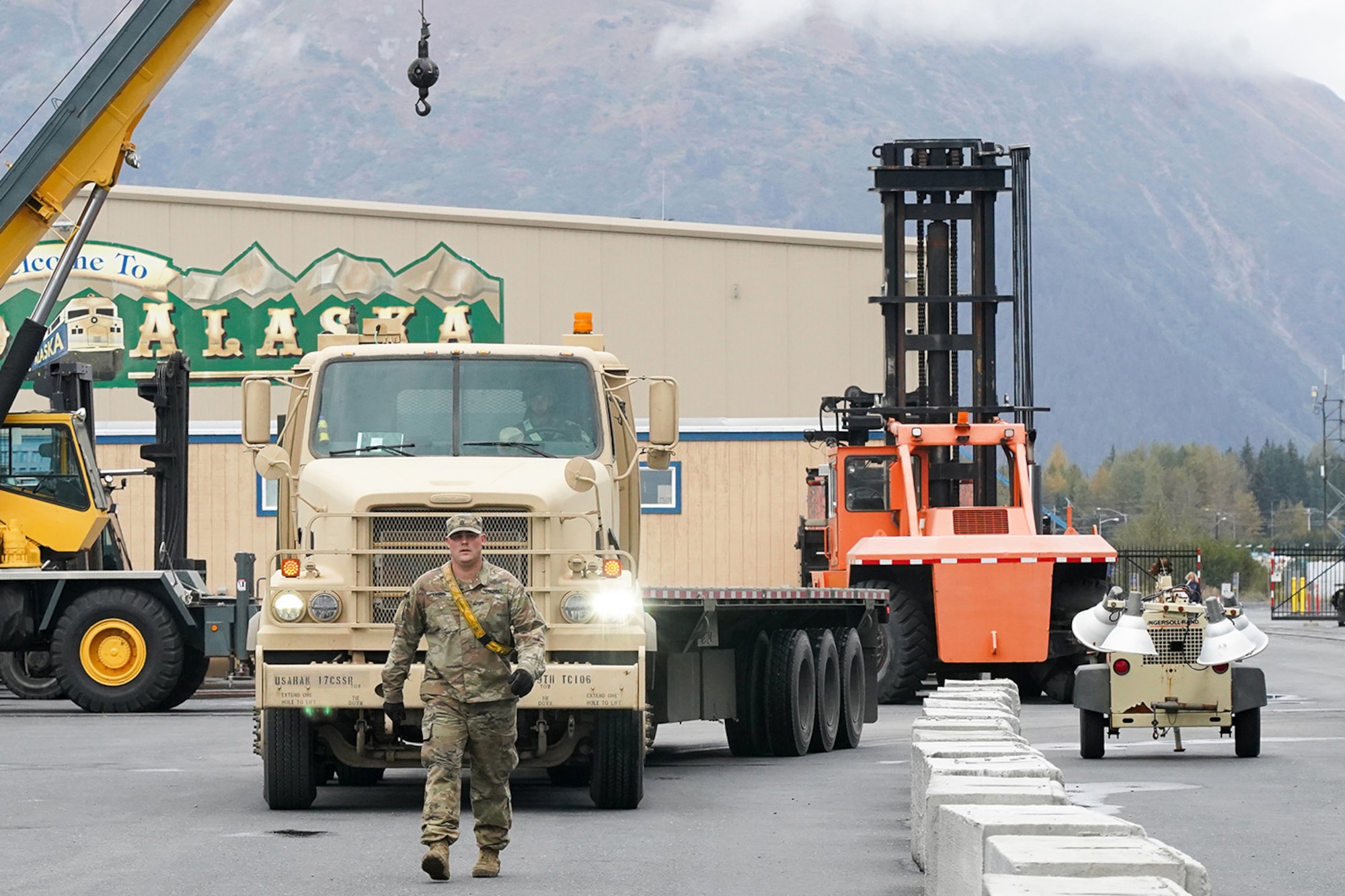 Army Sgt. Dylan Knigge, assigned to the 109th Transportation Company, 17th Combat Support Sustainment Battalion, U.S. Army Alaska, ground guides a M915A5 tractor with an M872 trailer to a staging area for loading U.S. Marine Corps bulk fuel supplies and equipment from the U.S.S. Comstock (LSD-45), a Whidbey Island-class dock landing ship, at the port of Seward, Alaska, Sept. 19, 2019, for transport to Joint Base Elmendorf-Richardson, Alaska. The U.S. Navy is conducting an Arctic Expeditionary Capabilities Exercise to test its logistical effectiveness and joint-service interoperability while responding to conflict or disaster in an austere environment with no organic assets.