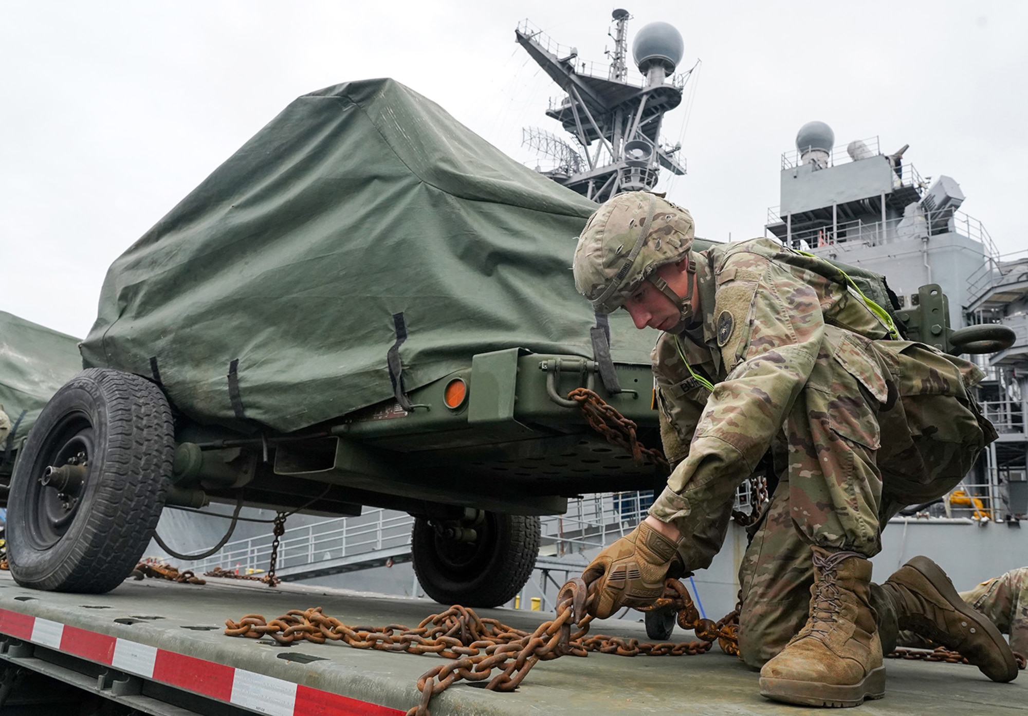 Specialist Timothy Burns, assigned to the 109th Transportation Company, 17th Combat Support Sustainment Battalion, U.S. Army Alaska, secures U.S. Marine Corps bulk fuel supplies and equipment from the U.S.S. Comstock (LSD-45), a Whidbey Island-class dock landing ship, to an M872 trailer at the port of Seward, Alaska, Sept. 19, 2019, for transport to Joint Base Elmendorf-Richardson, Alaska. The U.S. Navy is conducting an Arctic Expeditionary Capabilities Exercise to test its logistical effectiveness and joint-service interoperability while responding to conflict or disaster in an austere environment with no organic assets.
