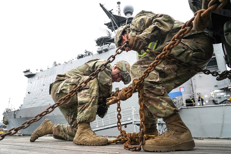 Army Sgt. Dylan Knigge, left, and Specialist Timothy Burns, both assigned to the 109th Transportation Company, 17th Combat Support Sustainment Battalion, U.S. Army Alaska, secure U.S. Marine Corps bulk fuel supplies and equipment from the U.S.S. Comstock (LSD-45), a Whidbey Island-class dock landing ship, to an M872 trailer at the port of Seward, Alaska, Sept. 19, 2019, for transport to Joint Base Elmendorf-Richardson, Alaska. The U.S. Navy is conducting an Arctic Expeditionary Capabilities Exercise to test its logistical effectiveness and joint-service interoperability while responding to conflict or disaster in an austere environment with no organic assets.