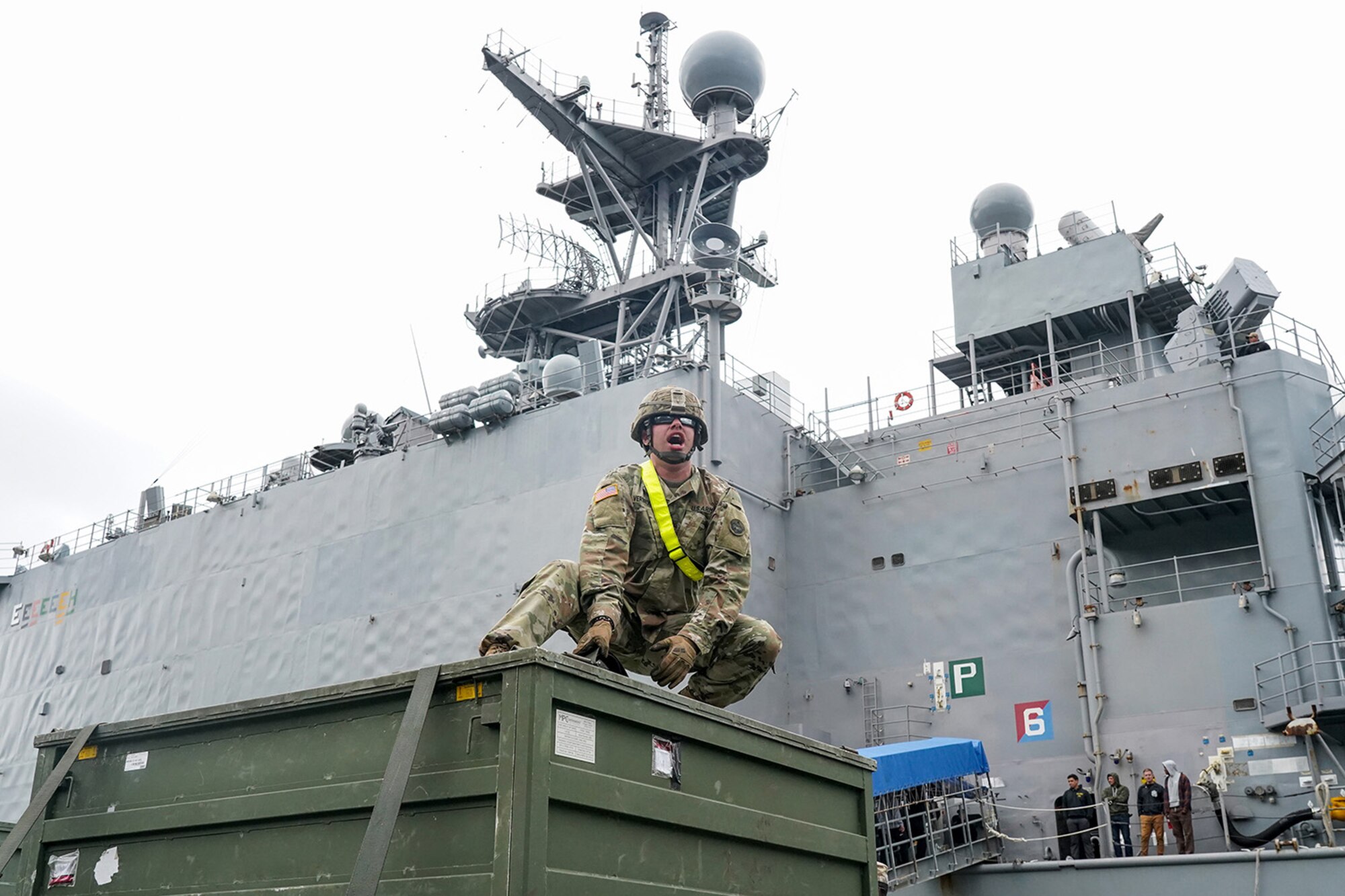 Specialist Zachary Verbruggen, assigned to the 109th Transportation Company, 17th Combat Support Sustainment Battalion, U.S. Army Alaska, yells to fellow Soldiers while securing U.S. Marine Corps bulk fuel supplies and equipment from the U.S.S. Comstock (LSD-45), a Whidbey Island-class dock landing ship, on an M872 trailer at the port of Seward, Alaska, Sept. 19, 2019, for transport to Joint Base Elmendorf-Richardson, Alaska. The U.S. Navy is conducting an Arctic Expeditionary Capabilities Exercise to test its logistical effectiveness and joint-service interoperability while responding to conflict or disaster in an austere environment with no organic assets.