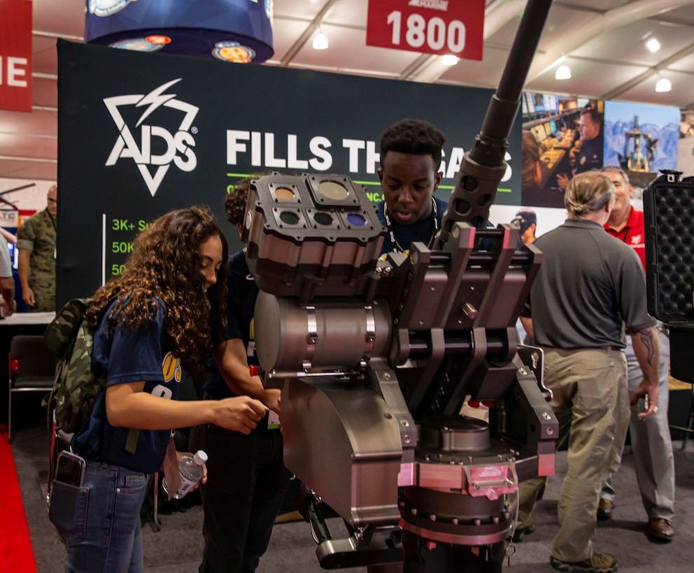 Students from Osbourn Park High School examine the Gyro-Stabilized Crew-Served Weapons Mount at the 2019 Modern Day Marine Expo on Marine Corps Base Quantico, Va., Sept. 19, 2019. Modern Day Marine is an expo which allows Marines to see the new premier military equipment, systems, services and technology that can be purchased to support the military in the future.
