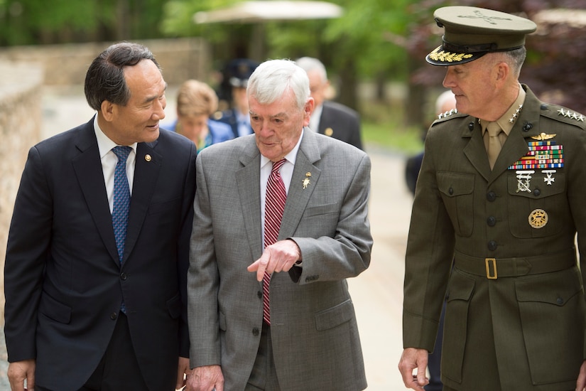 Three men speak while walking.