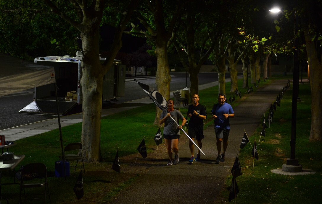 Members of Team Kirtland run with the POW/MIA flag during the 24-hour run or walk event at Kirtland Air Force Base, N.M., Sept. 19, 2019. At the conclusion of the run, members of the 351st Special Warfare Training Squadron carried the flag to its post at the memorial site where members of the community and Team Kirtland honored former POW/MIAs. (U.S. Air Force photo by Senior Airman Enrique Barceló)