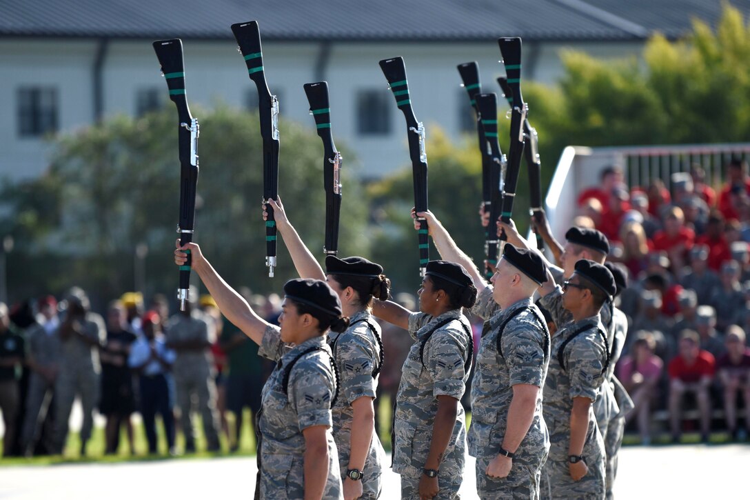 A group of airman hold up their weapons in the sky.