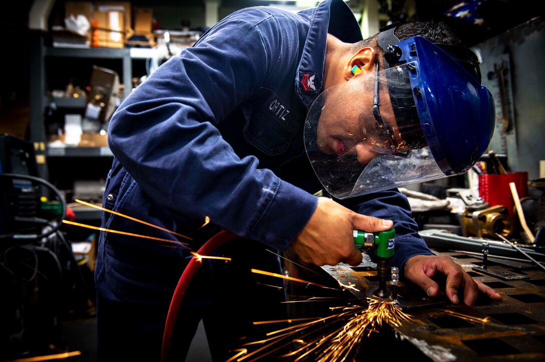 Sparks fly as a welder works on a bracket on a ship.