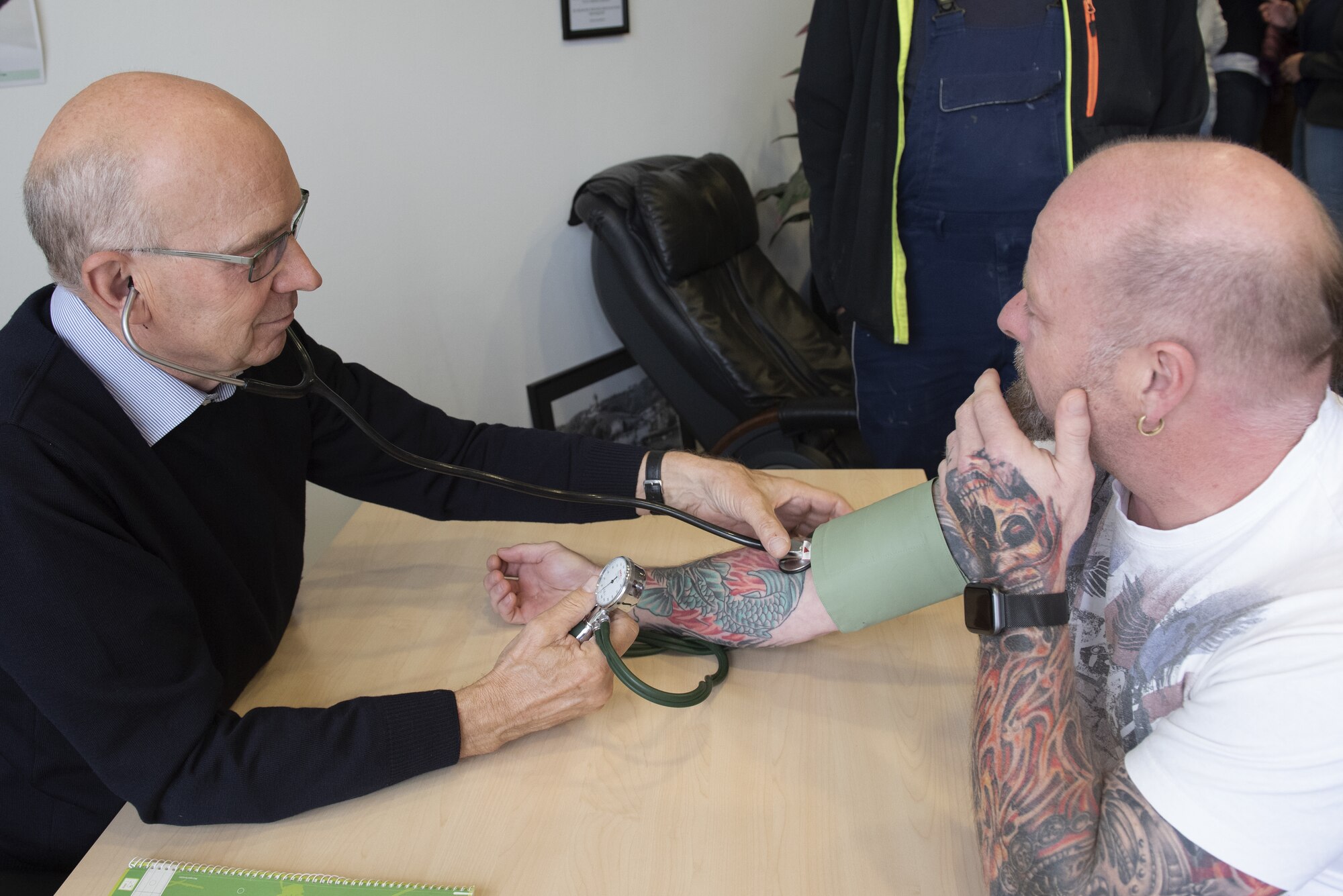 Gunter Willenborg, a local-national doctor of occupational health, left, takes the blood pressure of a health fair attendee at Spangdahlem Air Base, Germany, Sept. 24, 2019. Willenborg offered a free assessment to participants during the first local-national health fair. (U.S. Air Force photo by Airman 1st Class Alison Stewart)