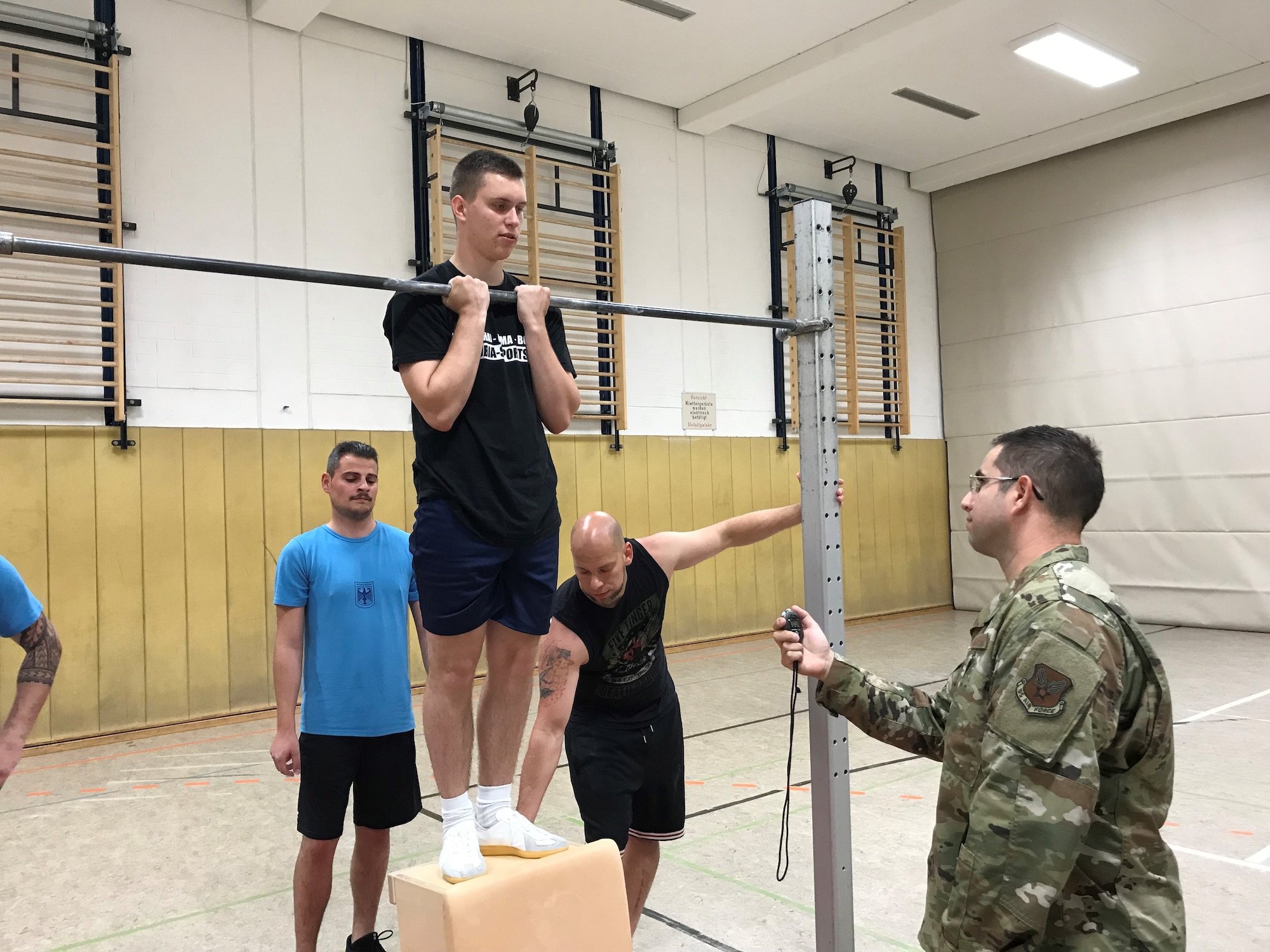 U.S. Air Force Tech. Sgt. Emmanuel Villasenor, right, German NCO Academy instructor, evaluates a student during a basic fitness test June 25, 2019 at the academy on Marseille Kaserne, Appen, Germany. The German airmen must able to hang from the bar for at least 15 seconds. Villasenor is one of only three enlisted members in Europe serving under the U.S. Air Force Military Personnel Exchange Program. (Courtesy photo)