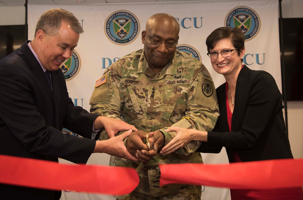 Three people cut a red ribbon.