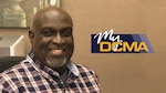 Photo of smiling man sitting in his cubicle