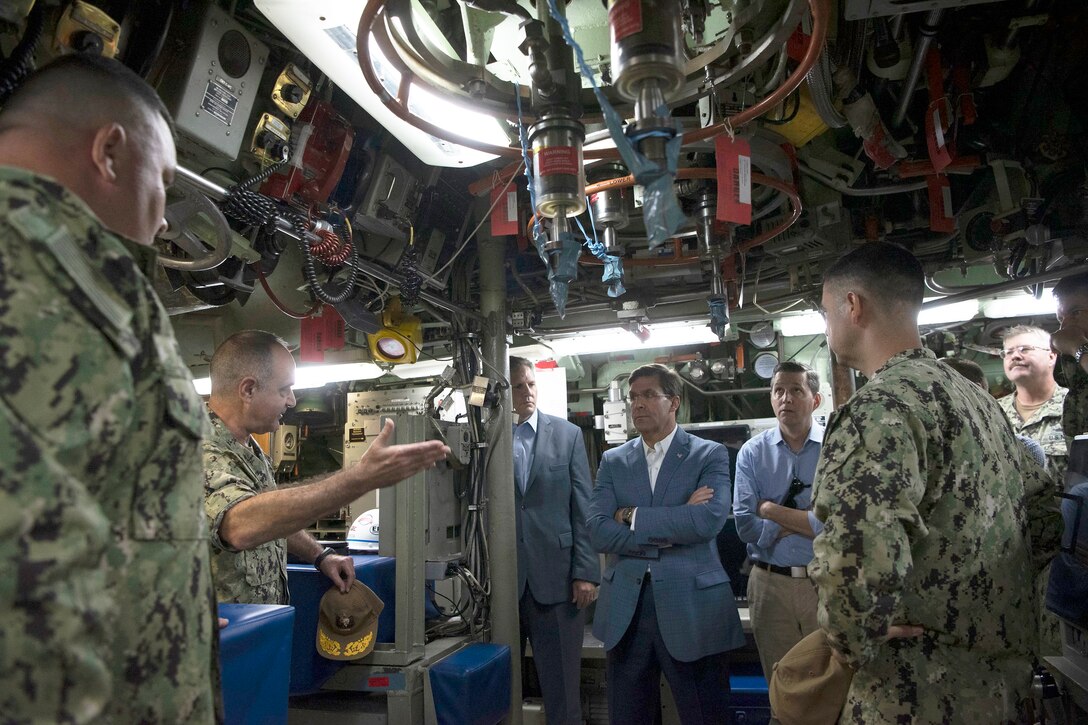 Defense Secretary Dr. Mark T. Esper talks to Navy officers during a tour of a submarine.