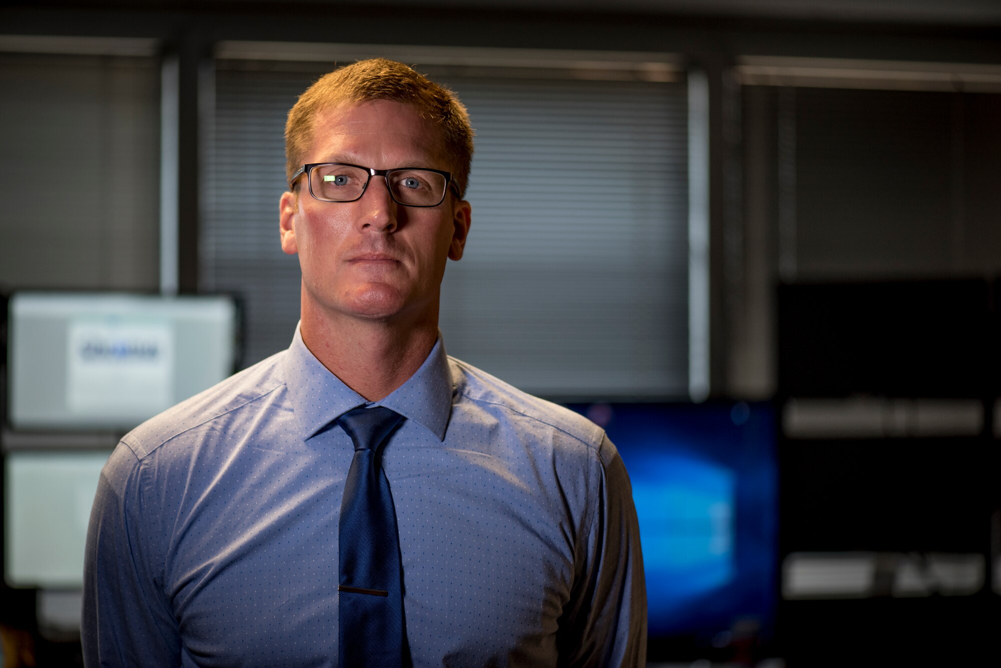 Environmental portrait photo of a military member standing in front of a computer