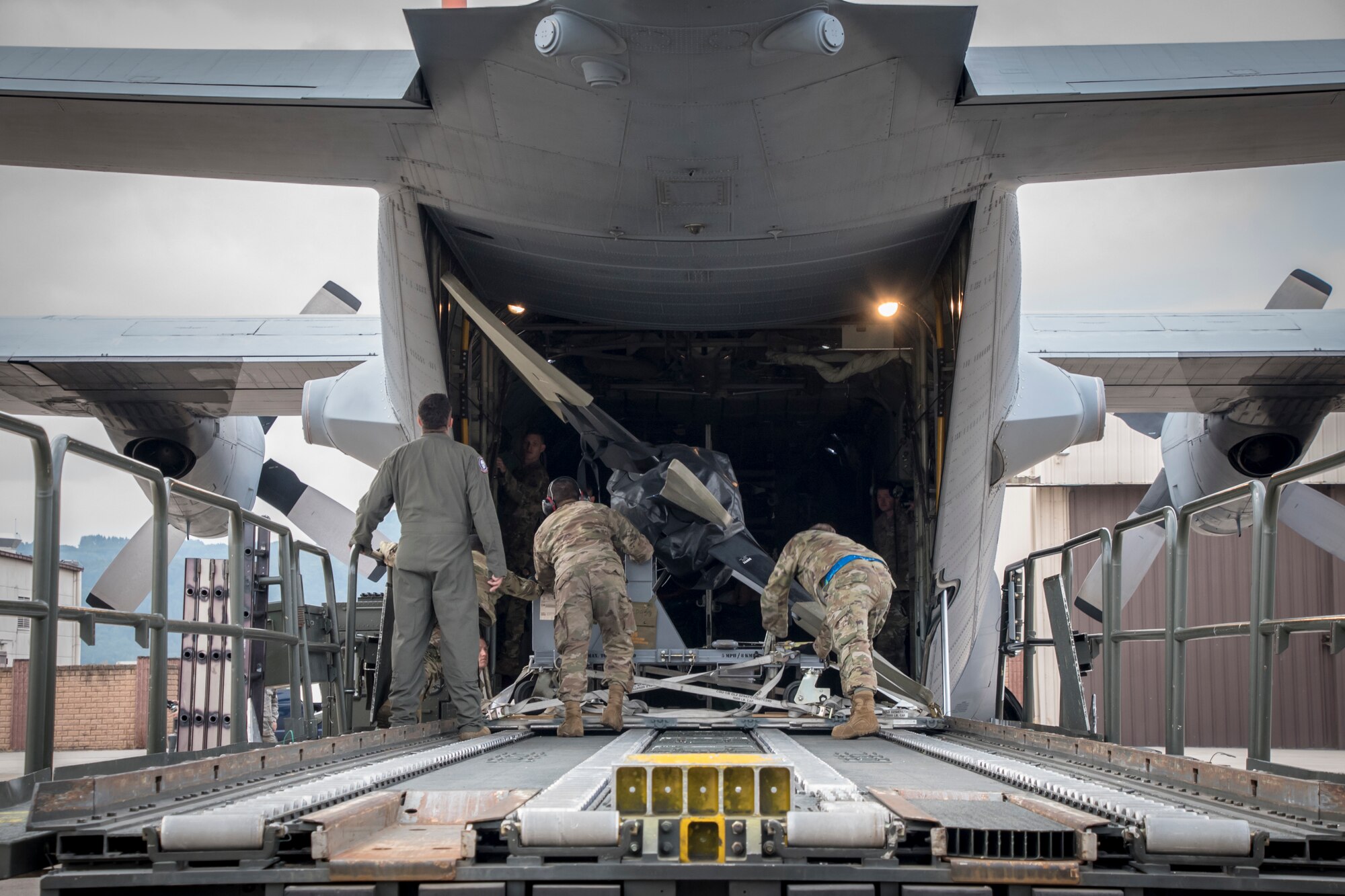 Photo of three military members removing equipment from a C-130.