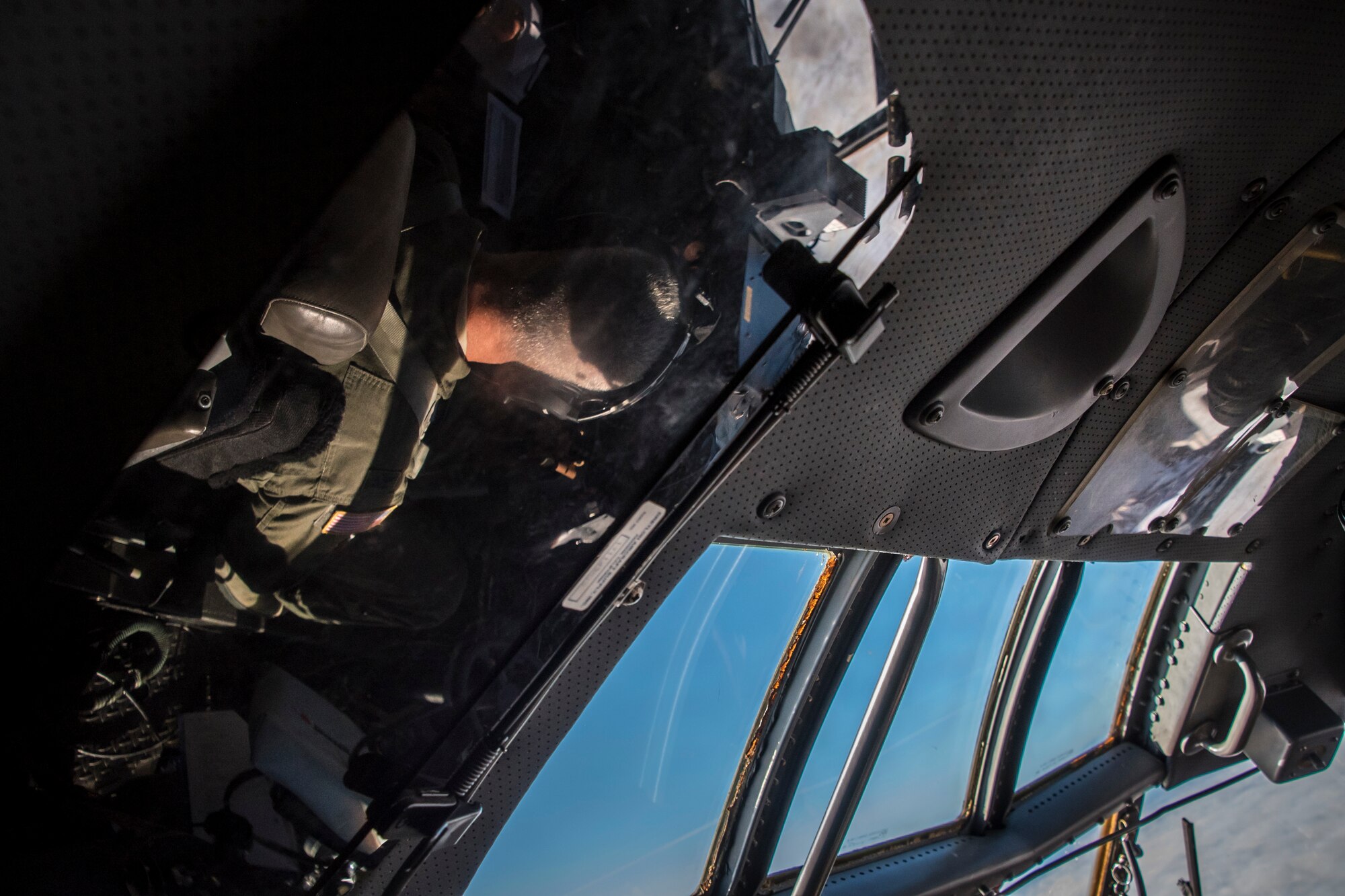 Abstract photo of the C-130 flight deck with pilot reflections in mirrors and windows.