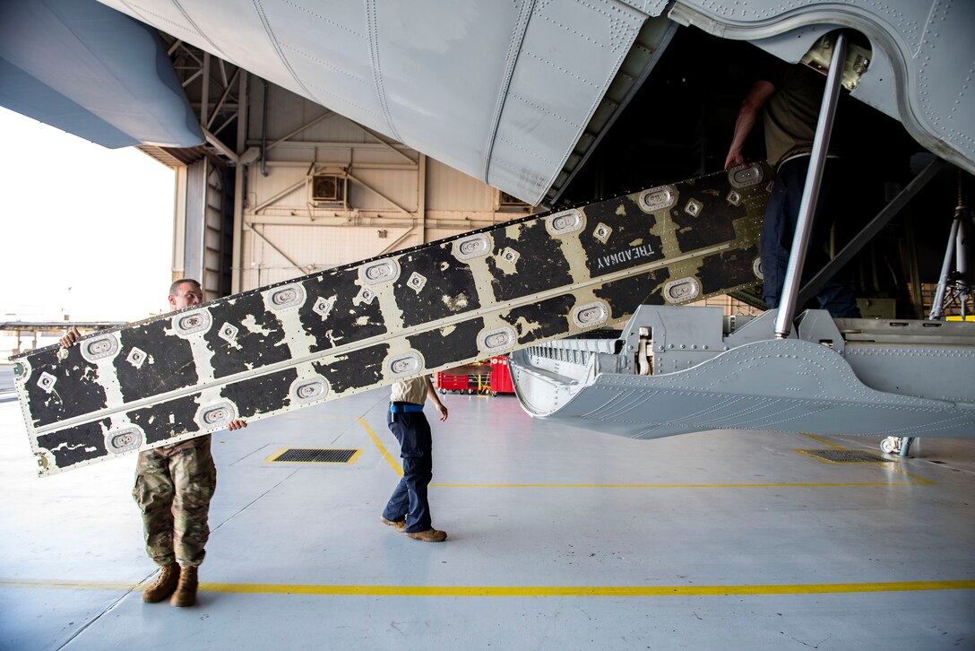 Staff Sgt. Zachary Haskell, left, and Staff Sgt. Zachary Morales, 71st Aircraft Maintenance Unit crew chiefs, transport a cargo floor panel during preparation of an HC-130J Combat King II for a situational awareness communication upgrade (SACU) modification Sept. 25, 2019, at Moody Air Force Base, Ga. The panels are removed to allow access to the area inside the aircraft where the SACU will be installed. This SACU will enhance the aircraft’s ability to communicate with personnel on the ground during search and rescue operations. (U.S. Air Force photo by Senior Airman Erick Requadt)