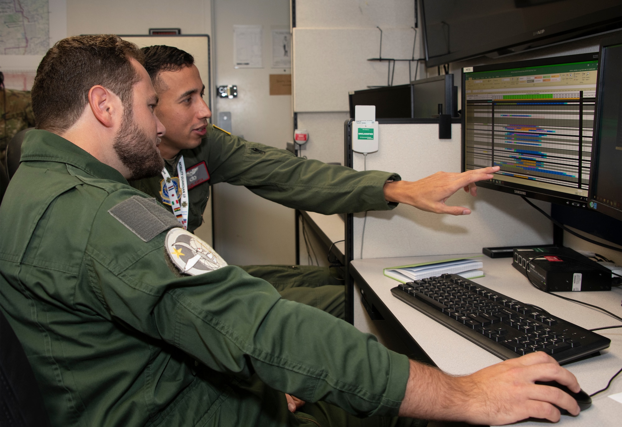 French Air Force Lt. Rodelphe Barberot, left, Escadron de transport 2/61 Franche-Comté, and U.S. Air Force Capt. Miguel Garcia, center, 321st Air Mobility Operations Squadron assistant operations officer, study data files at the Weapons Systems Suite in the Air Operations Center during exercise Mobility Guardian Sept. 25, 2019, at Travis Air Force Base, California. MG19 is Air Mobility Command’s flagship exercise for large-scale, rapid global mobility operations. Forty-six U.S. aircraft joined aircraft from 29 international partners, along with more than 4,000 U.S. and international Air Force, Army, Navy and Marine Corps aviators. (Photo altered for security reasons)  (U.S. Air Force photo illustration by Heide Couch)