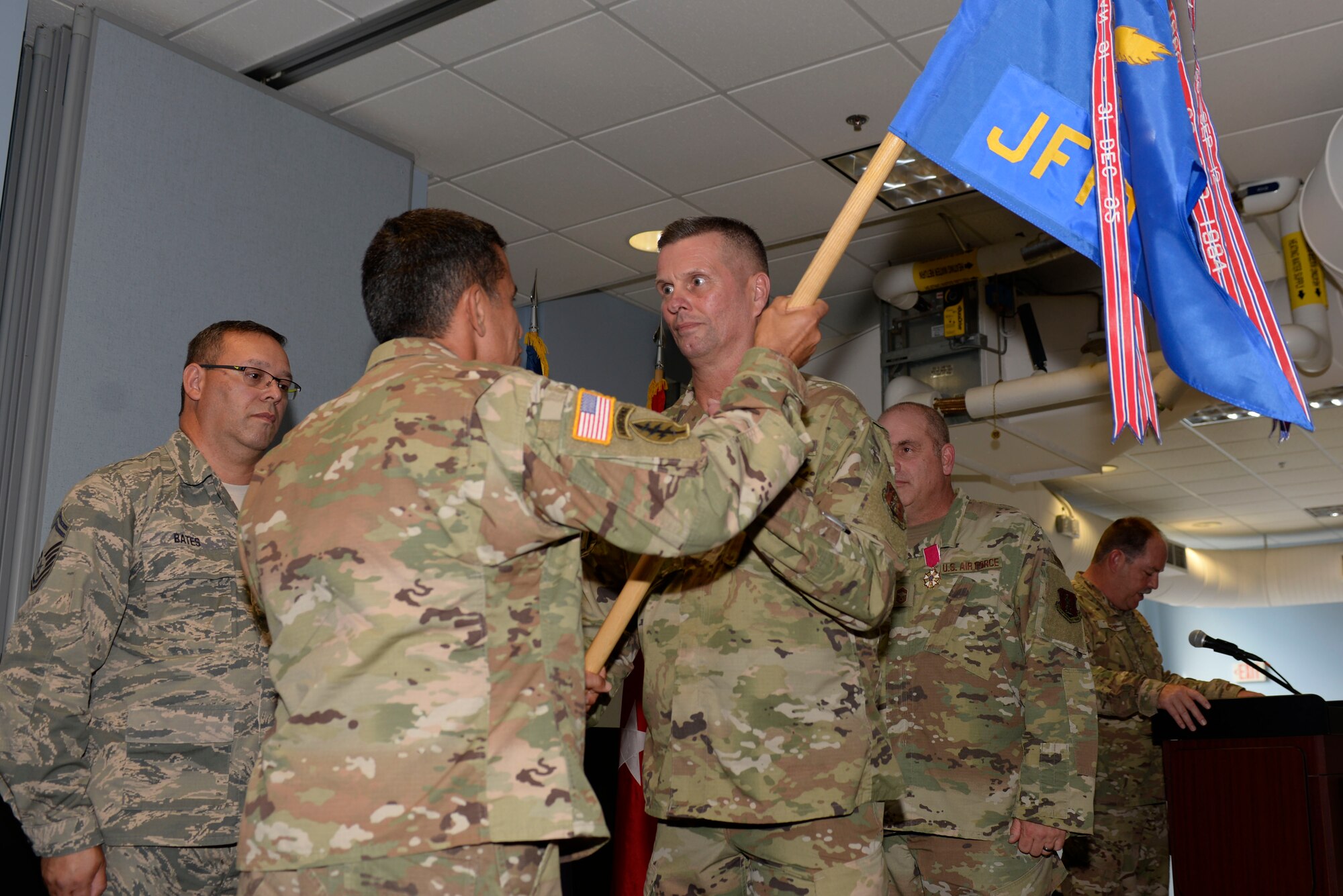 Chief Master Sgt. John Symington accepts the joint force headquarters guidon from Maj. Gen. David Mikolaities, adjutant general, New Hampshire National Guard, during an assumption of authority ceremony at Pease Air National Guard Base, Sept. 15, 2019. Symington assumed the state command chief postion during the ceremony.(U.S. Air National Guard photo by Senior Airman Taylor Queen)
