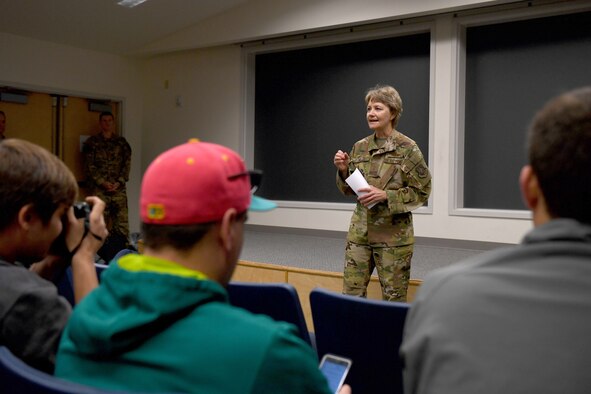 A woman in uniform talks to people in regular clothes.