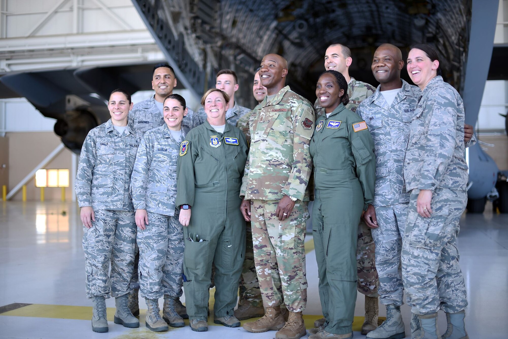 Chief Wright is surrounded by Airmen in an aircraft hangar. They're posing for a picture. They're smiling.