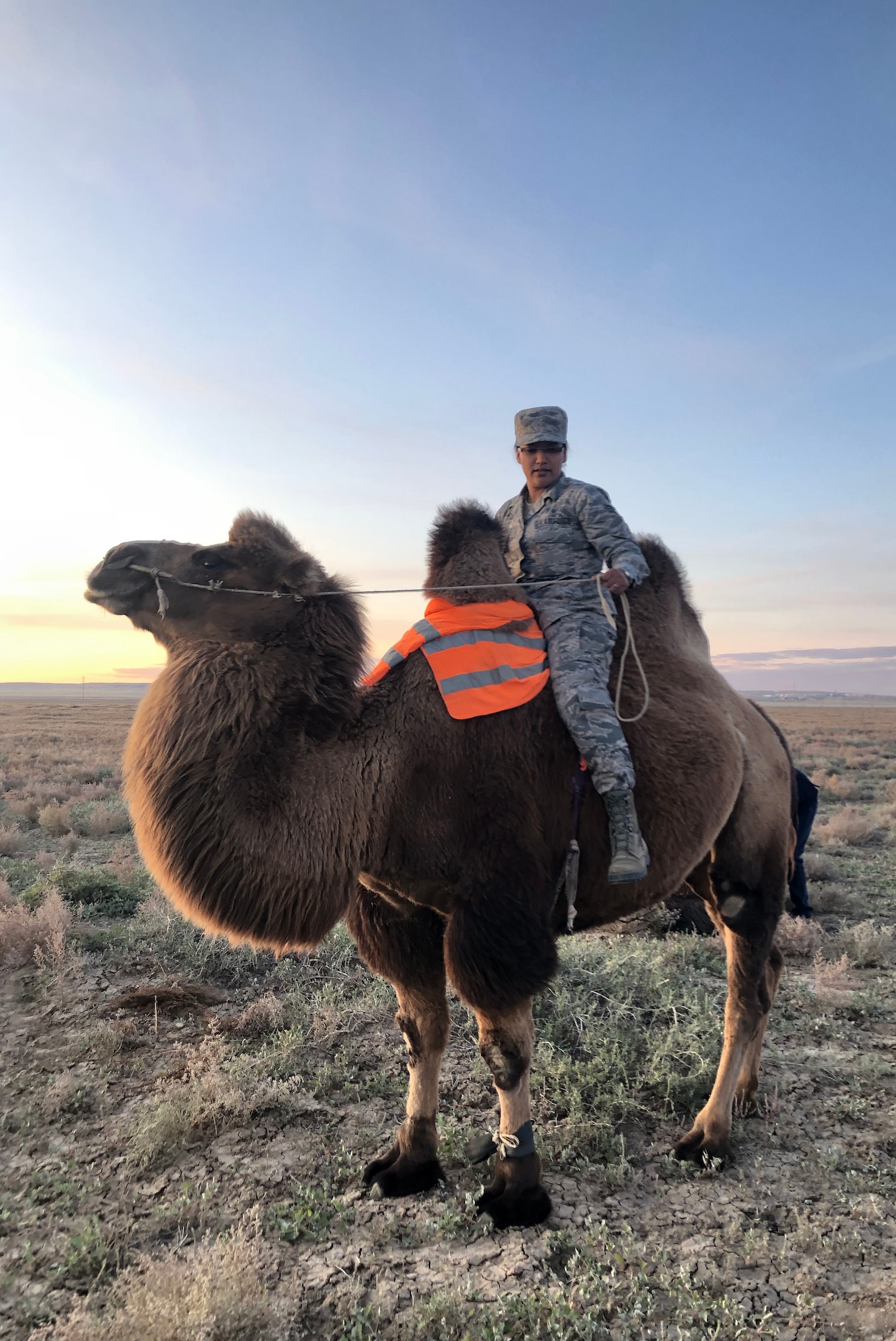 U.S. Air Force Senior Airman Liana Chythlook, assigned to the 176th Medical Group, Alaska Air National Guard, rides a Bactrian camel Sept. 20, 2019,  at a farm during Gobi Wolf 2019 in Sainshand, Mongolia. GW 19 was hosted by the Mongolian National Emergency Management Agency and Mongolian Armed Forces as part of the United States Army Pacific's humanitarian assistance and disaster relief "Pacific Resilience" series. (Courtesy photo/Released)