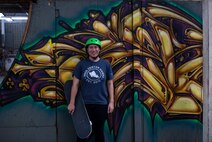 Skateboarder poses in front of graffiti