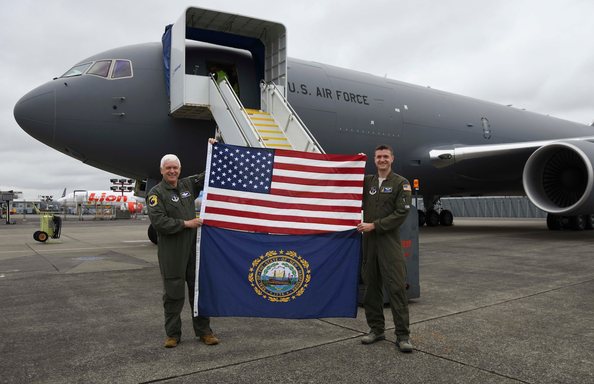 U.S. Air Force Lt. Gen. L. Scott Rice, left, director of the Air National Guard, and U.S. Air Force Capt. Lee
Rice, right, a pilot assigned to the 157th Air Refueling Wing, Pease Air National Guard Base, New
Hampshire, hold the flag of the United States and the state flag of New Hampshire in front of a KC-46A
Pegasus at the Boeing Distribution Center, Seattle, Wash., Aug. 8, 2019. This KC-46 was flown by the Rice
father-and-son duo to the aircraft’s newly assigned home station at the 157th ARW. (U.S. Air National
Guard photo by Staff Sgt. Morgan R. Lipinski)