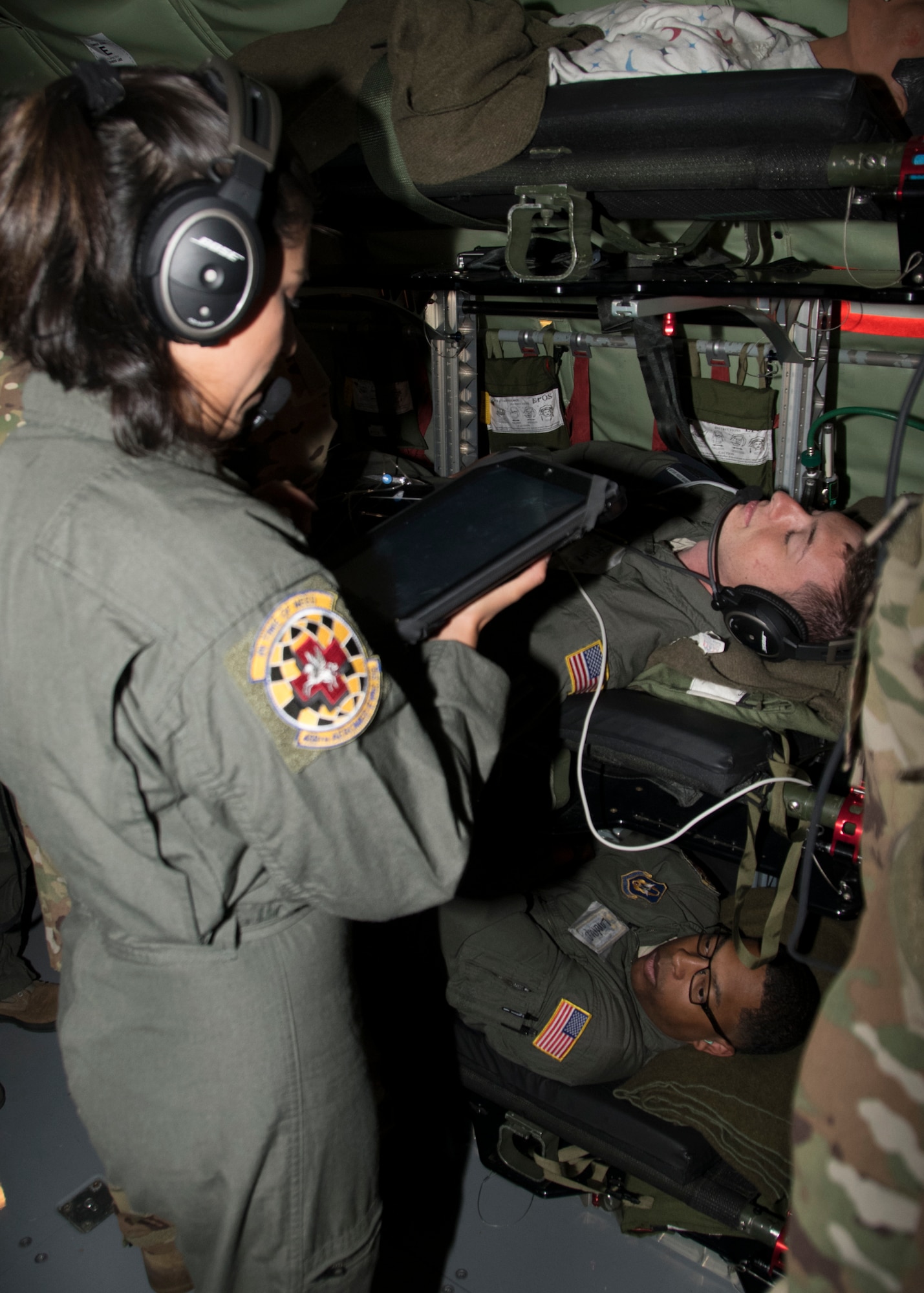 Senior Airman Maria Moposita, 459th Aeromedical Evacuation Squadron flight medic, checks on her patient mid-flight as part of an off station trainer Sept. 20, 2019. The AES team conducted training on a KC-135 Stratotanker during a flight to Wright Patterson, Ohio, where they later participated in the Air Force Marathon. (U.S. Air Force photo by Staff Sgt. Cierra Presentado/Released)