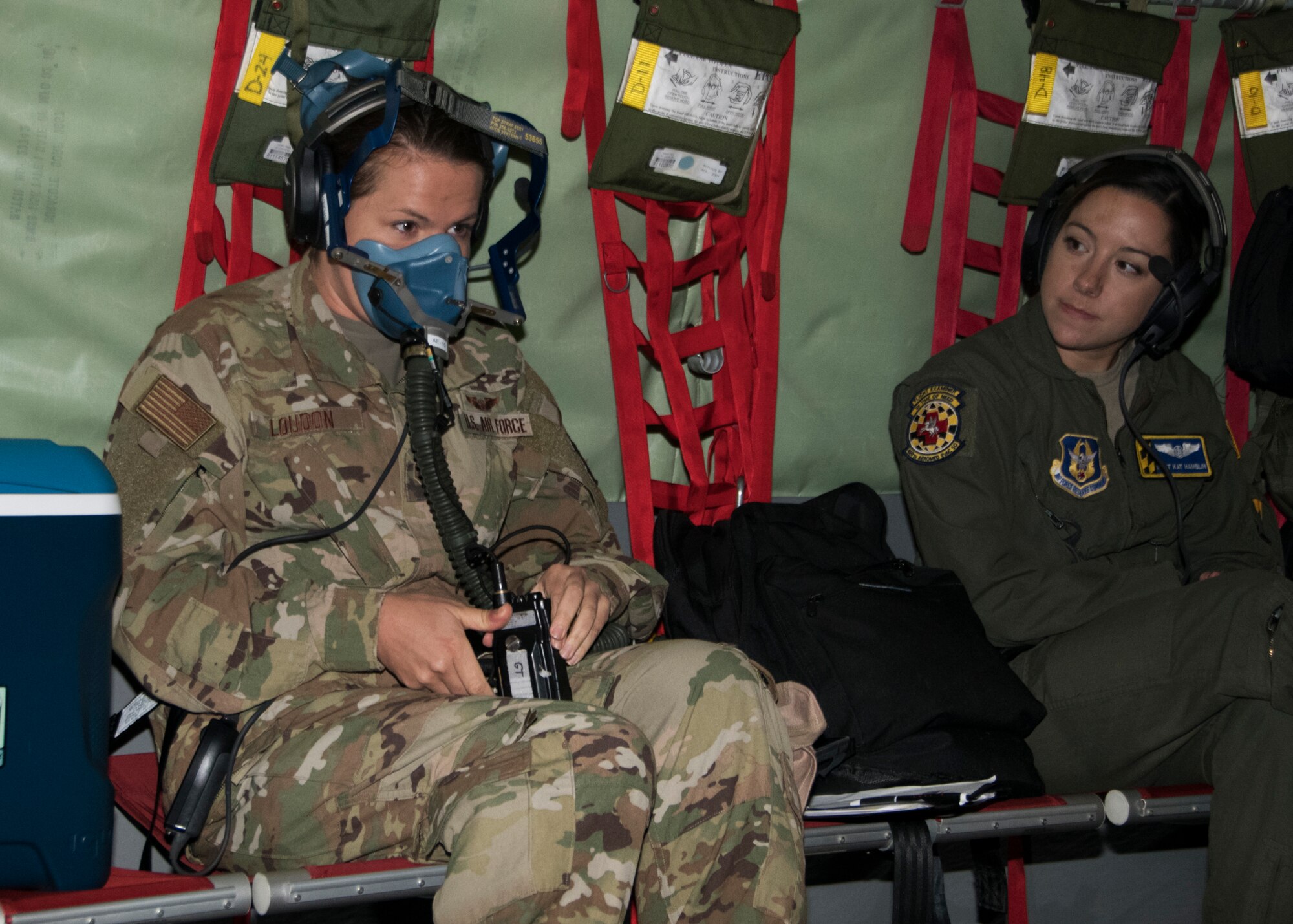 Staff Sgt. Sarah Loudon, 459th Aeromedical Evacuation Squadron flight medic, puts on an oxygen mask as part of an in-flight aircraft emergency as Master Sgt. Kat Hamblin, 459 AES flight instructor observes, during an off  station trainer held on a KC-135 Stratotanker Sept. 20, 2019. The AES team conducted training during a flight to Wright Patterson, Ohio, where they later participated in the Air Force Marathon. (U.S. Air Force photo by Staff Sgt. Cierra Presentado/Released)