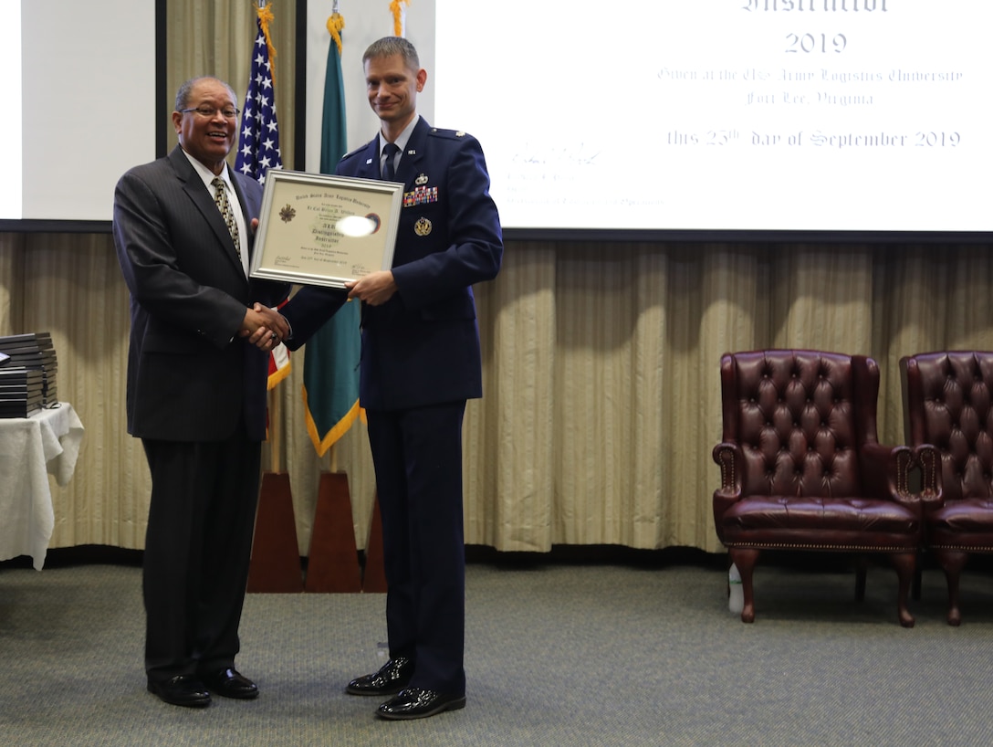 U.S. Air Force Lt. Col. Brian Wilken receives a 2019 Distinguished Instructor award from Michael Williams, Army Logistics University president during a ceremony at Fort Lee, Va., Sept. 25, 2019. Wilken is an instructor at the ALU College of Professional and Continuing Education, and earned the award for exceptional performance and significant achievements that greatly contributed to the success of ALU's academic and training mission. (U.S. Army photo / Dani Johnson)