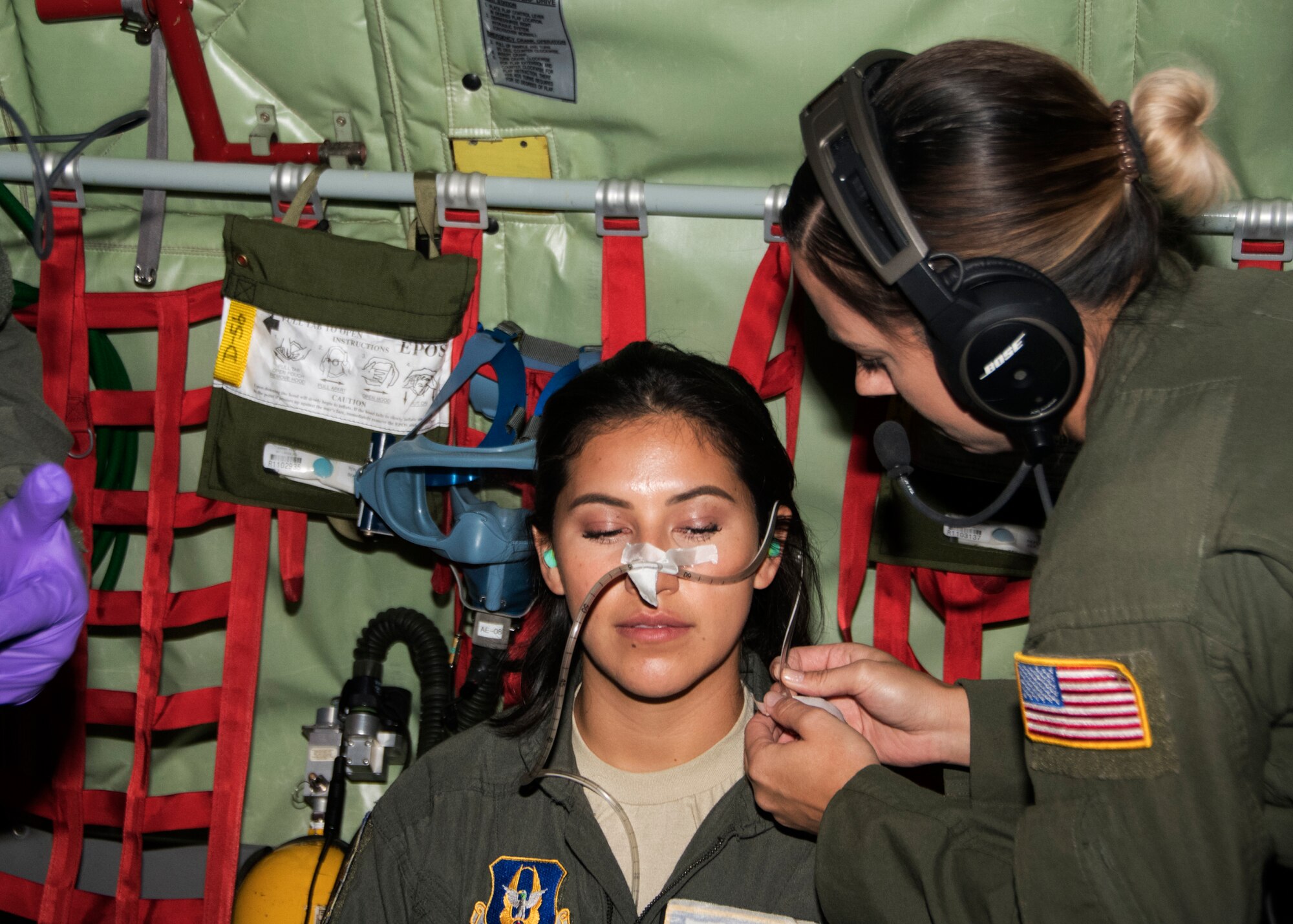 Master Sgt. Kat Hamblin, 459th Aeromedical Evacuation Squadron, shows a taping technique of a nasal gastric tube to protect its accidental removal on Senior Airman Maria Moposita during an off station trainer on a KC-135 Stratotanker, Sept. 20, 2019. The AES team conducted training during a flight to Wright Patterson, Ohio, where they later participated in the Air Force Marathon. (U.S. Air Force photo by Staff Sgt. Cierra Presentado/Released)