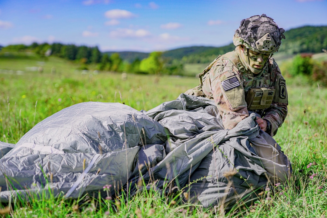 A soldier packs up a parachute.