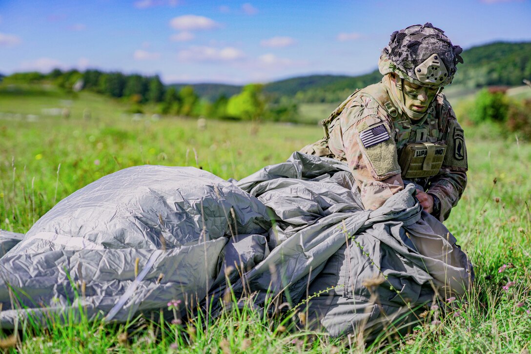 A soldier packs up a parachute.