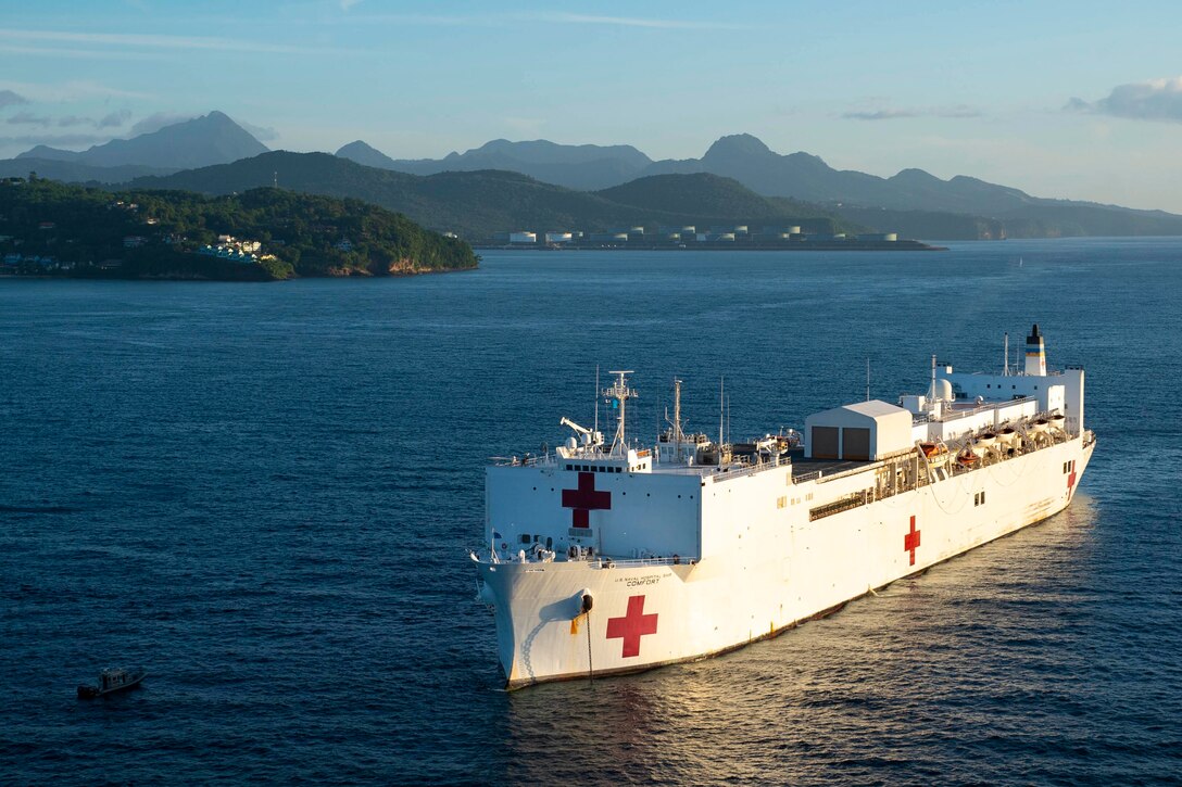 A ship anchored in water with mountains in the background.