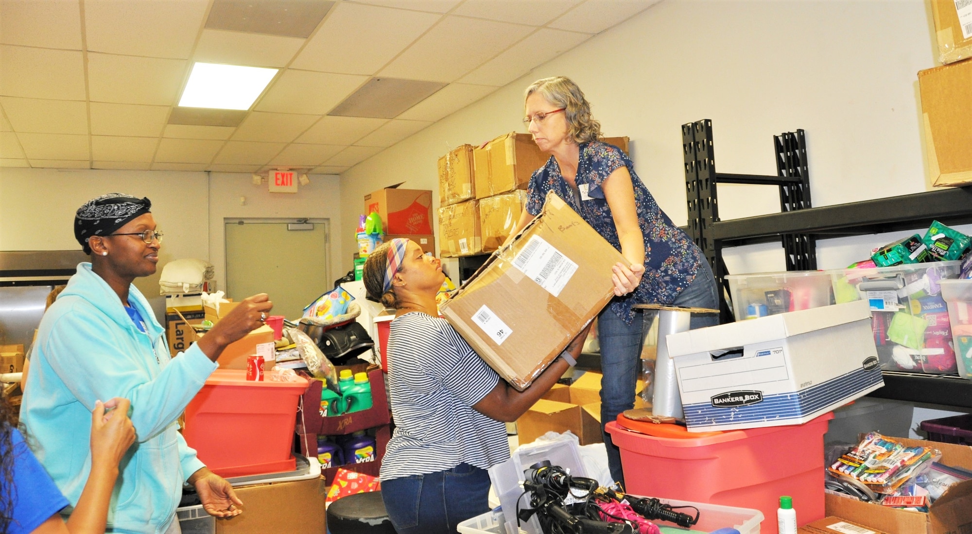 340th Flying Training Group volunteers (left to right) Master Sgt. Faith Wells, Capt. Yolanda Seals and Lt. Col. Teresa Davies move boxes of clothing to the sorting area at the Family Violence Prevention Services/Battered Women and Children’s Shelter’s Donation Center during the group's Sept. 11 community outreach event. (U.S. Air Force photo by Janis El Shabazz)