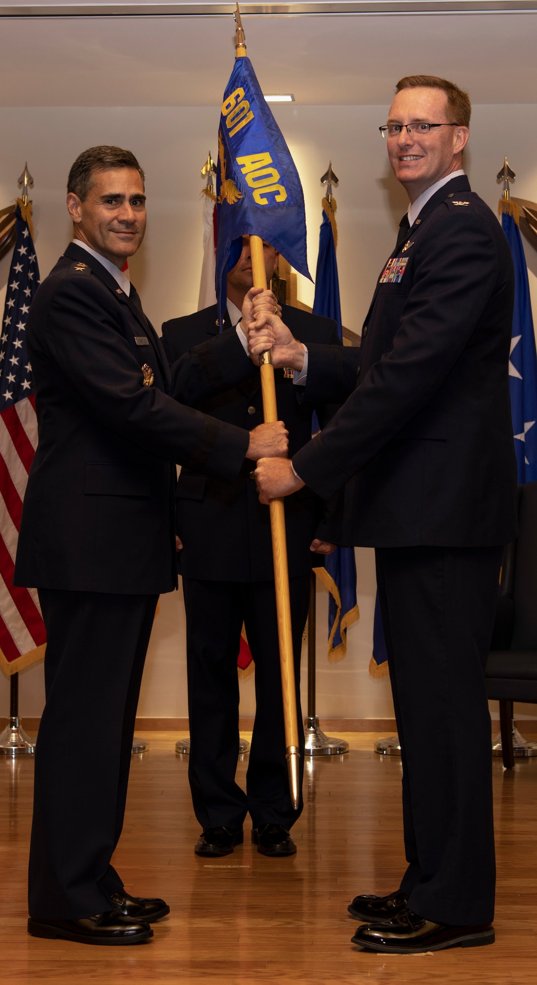 Col. Greg Krane, 101st Air and Space Operations Group commander, takes the ceremonial flag from Lt. Gen. Marc Sasseville, Continental U.S. North American Aerospace Defense Command Region - First Air Force (Air Forces Northern) commander, during the 601st Air Operations Center change of command ceremony at Tyndall Air Force Base, Florida on Sept. 26, 2019. The passing of the flag symbolizes Krane's acceptance of command of the 601st AOC. (U.S. Air Force photo by Senior Airman Cheyenne Larkin)