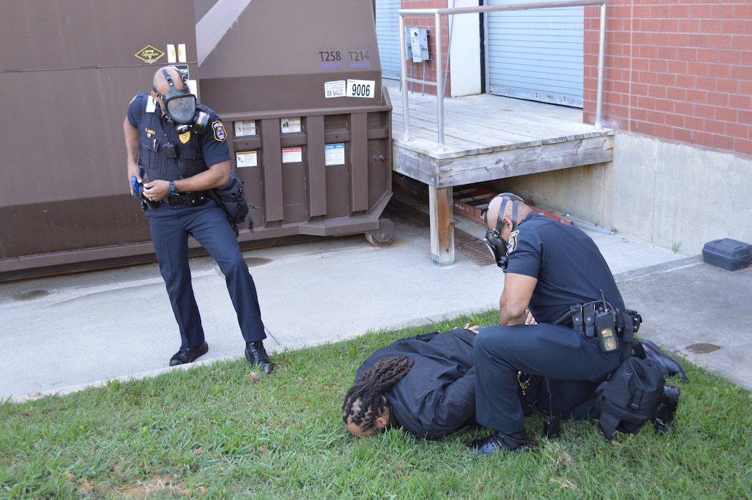 Two male police officers place another male under arrest during a simulated active shooter event.