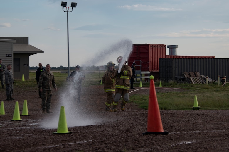 The team for the 97th Security Forces Squadron try to use a fire house to spray a tennis ball off of a traffic cone during the Squadron Commander and First Sergeant Challenge