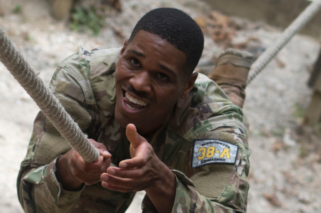 A soldier climbs across a one-rope bridge.