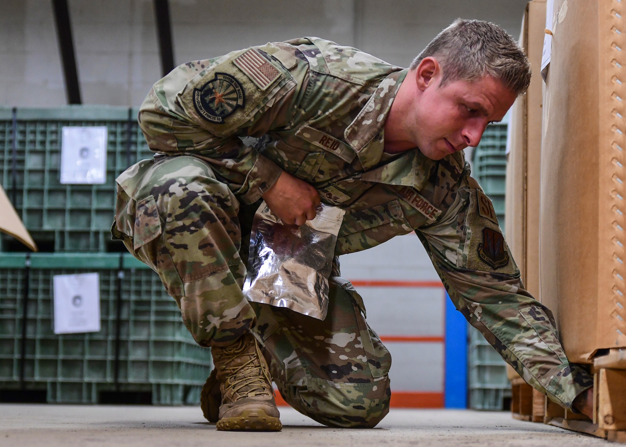 U.S. Air Force Staff Sgt. Joshua Reid, 355th Security Forces military working dog trainer, sets up a narcotic/explosive detection exercise for an MWD team at Davis-Monthan Air Force Base, Arizona, Sept. 24, 2019. MWDs are specialized in detecting either narcotics or explosives throughout their careers. (U.S. Air Force photo by Airman 1st Class Kristine Legate)